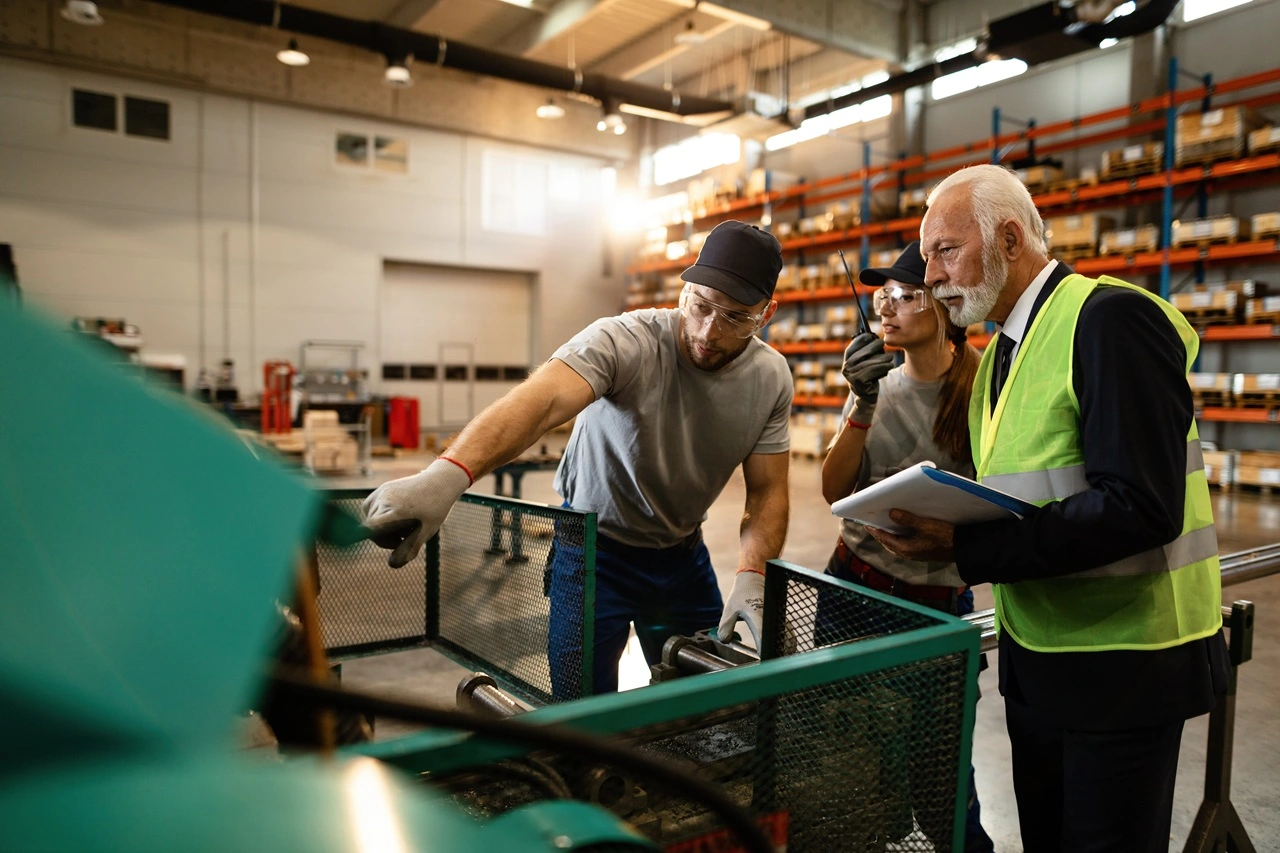 Profissionais avaliando máquina e processos em ambiente industrial para avaliação de serviços de engenharia industrial.